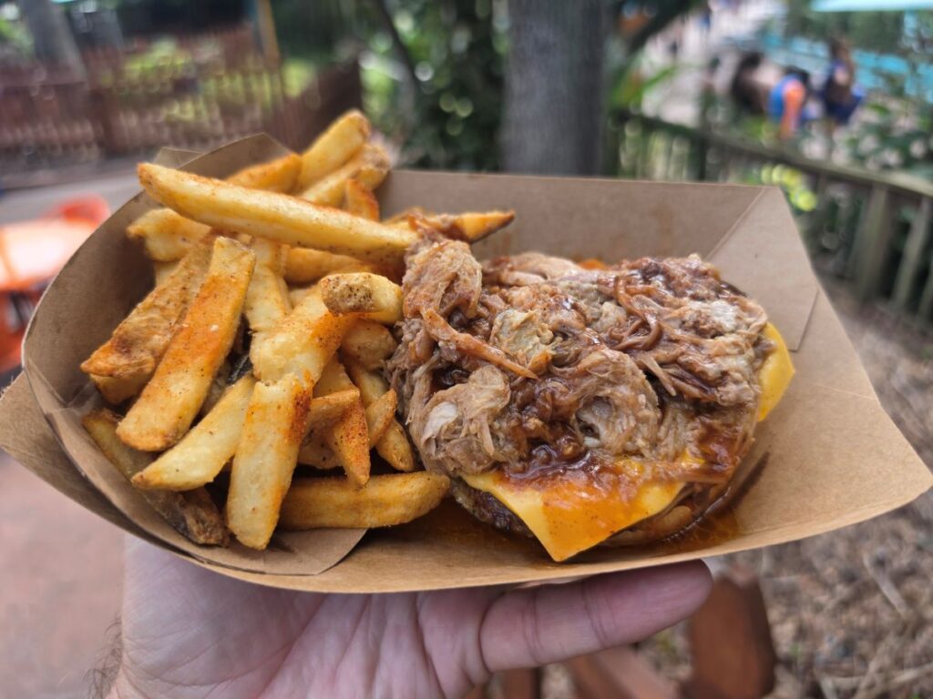 Top-down view of a BBQ pulled pork burger without top bun served with french fries in a cardboard tray