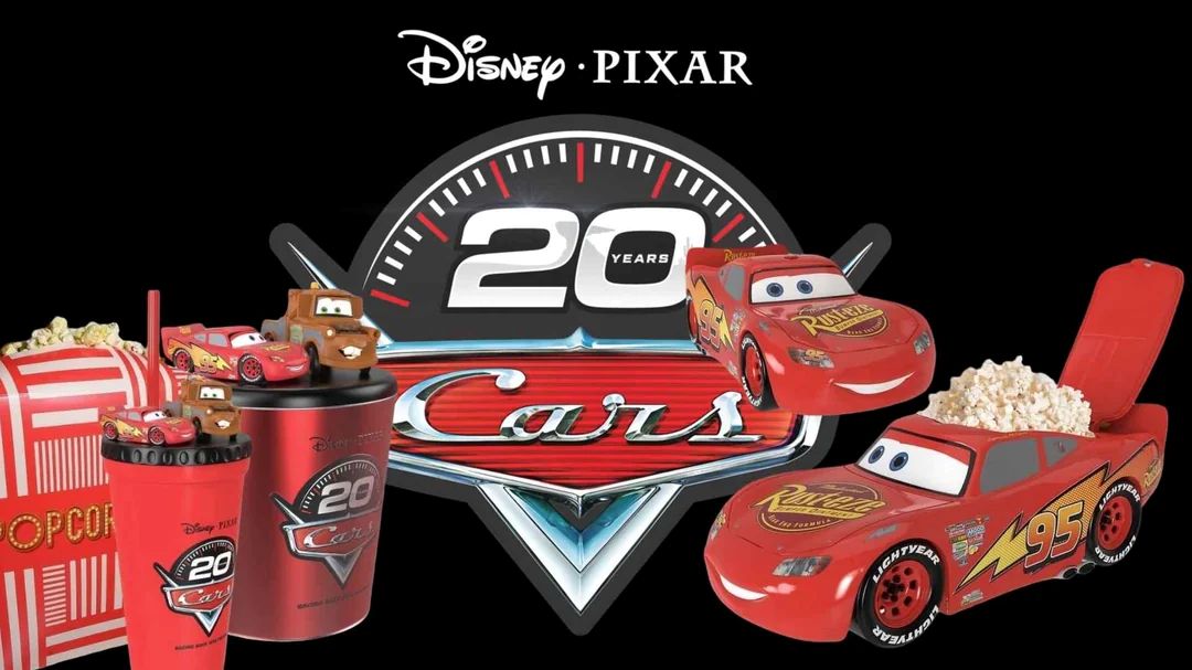 Disney Pixar Cars 20th anniversary merchandise featuring a popcorn bucket shaped like Lightning McQueen, themed cups, and a logo on a black background.