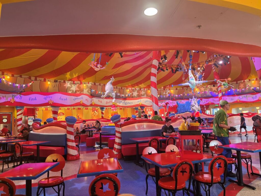 Colorful circus tent interior dining room of Circus McGurkus Cafe Stoo-pendous with red dining tables and overhead decorations.