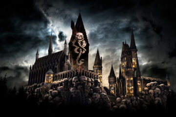A dark, gothic castle covered in a massive pile of human skulls under a stormy sky, with a glowing Dark Mark symbol projected on the central tower for Dark Arts Universal Orlando show