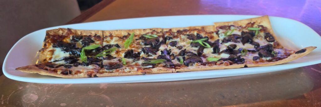 French onion flatbread topped with melted cheese, caramelized onions, and green onions at City Works.