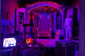 Retro horror TV studio set with gothic throne, jack-o'-lanterns, and film equipment in HHN Bloodengutz 2026 house