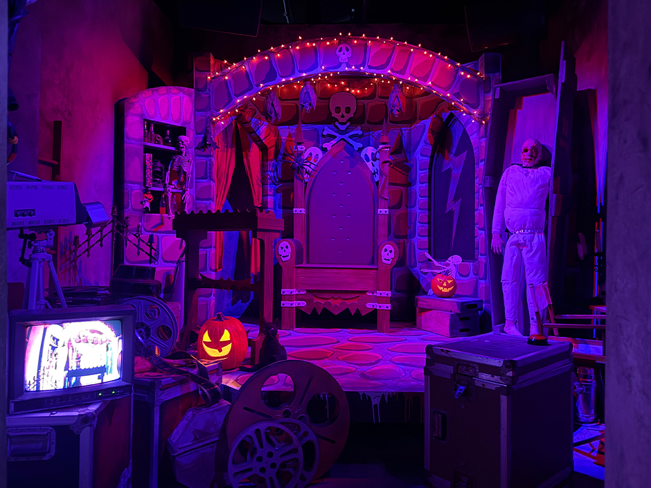 Retro horror TV studio set with gothic throne, jack-o'-lanterns, and film equipment in HHN Bloodengutz 2026 house