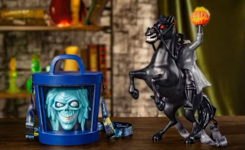A blue cylindrical Halloween Party popcorn bucket featuring a light-blue skull face and a headless horseman figure on a black horse holding a glowing orange pumpkin head.