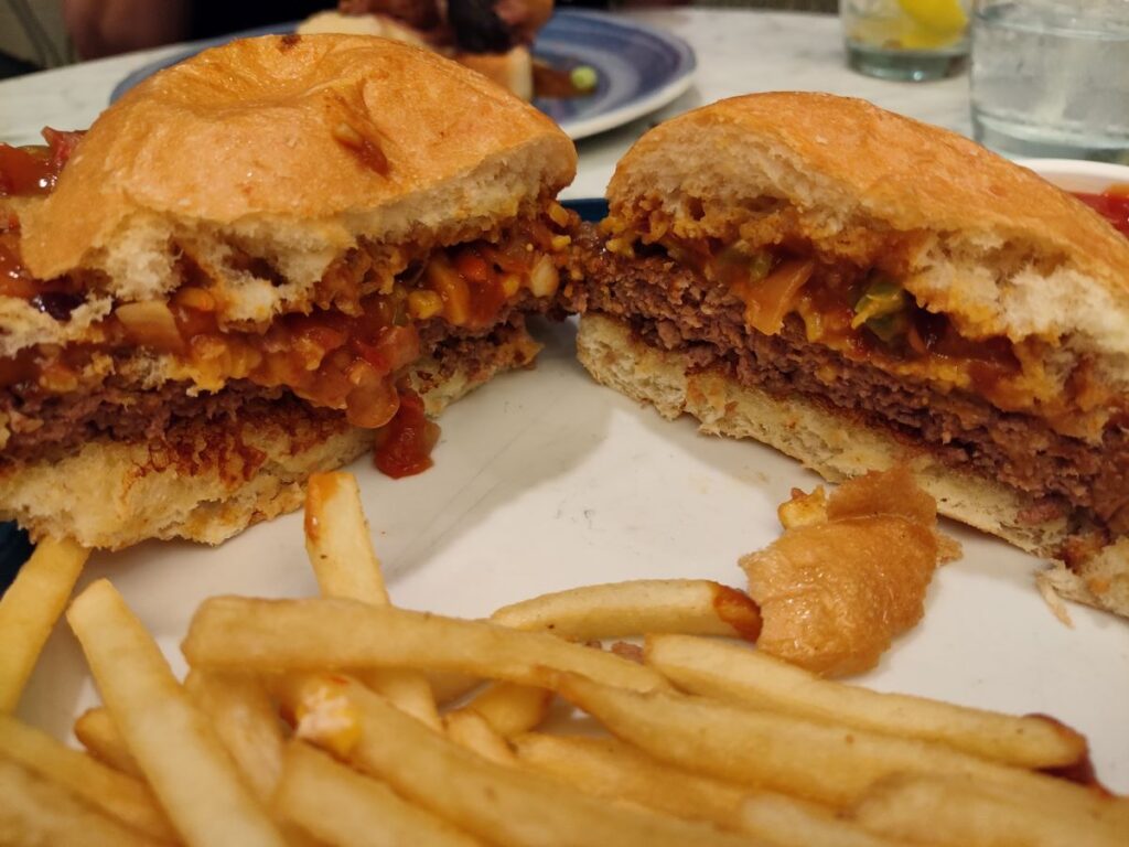 A cross-section view of a plant-based Chili Impossible Burger cut in half served with crispy fries at The Plaza Restaurant in Magic Kingdom.