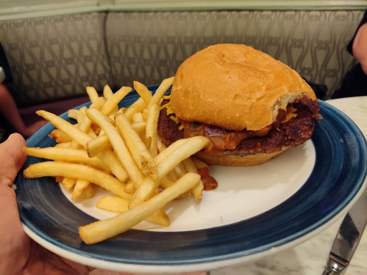 A Chili Impossible Burger with a side of french fries served on a blue-rimmed plate at The Plaza Restaurant.