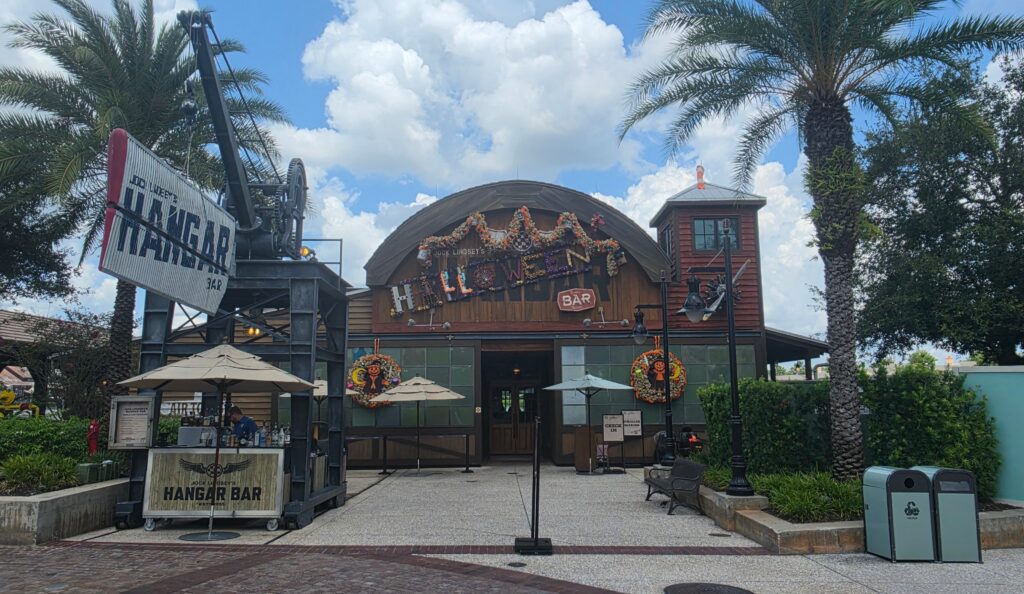 Exterior entrance of Jock Lindsey's Hangar Bar decorated for the Halloween season with themed signage and festive wreaths at Disney Springs.