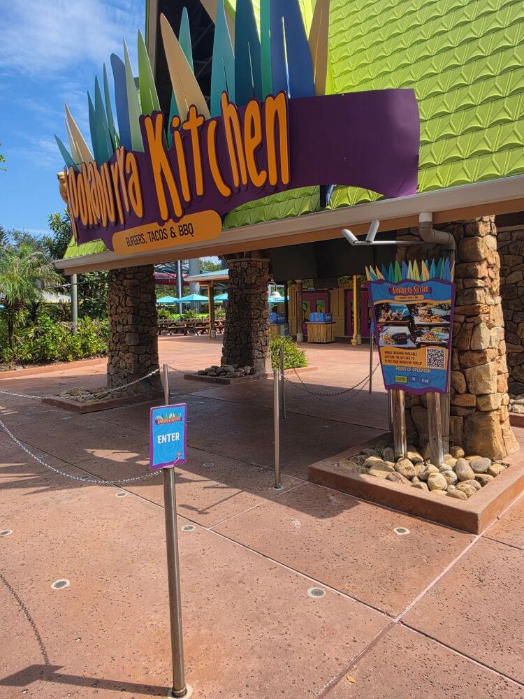 Entrance queue area of Kookaburra Kitchen quick-service restaurant at Aquatica Orlando with directional signage