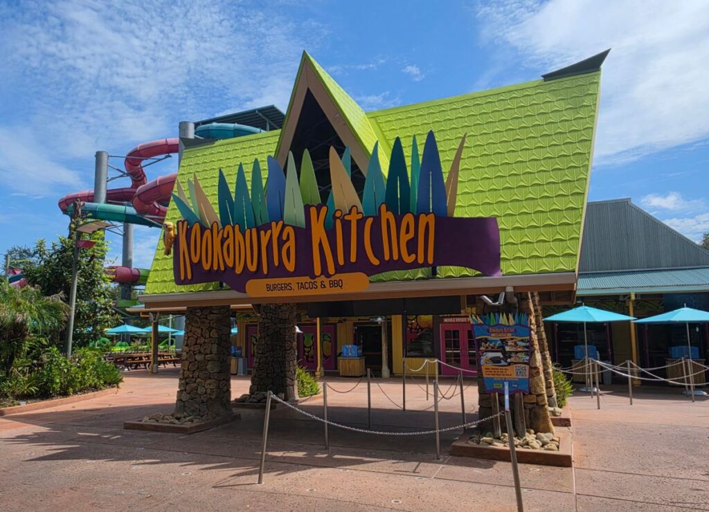 Exterior view of the colorful Kookaburra Kitchen restaurant building and entrance sign at Aquatica Orlando water park