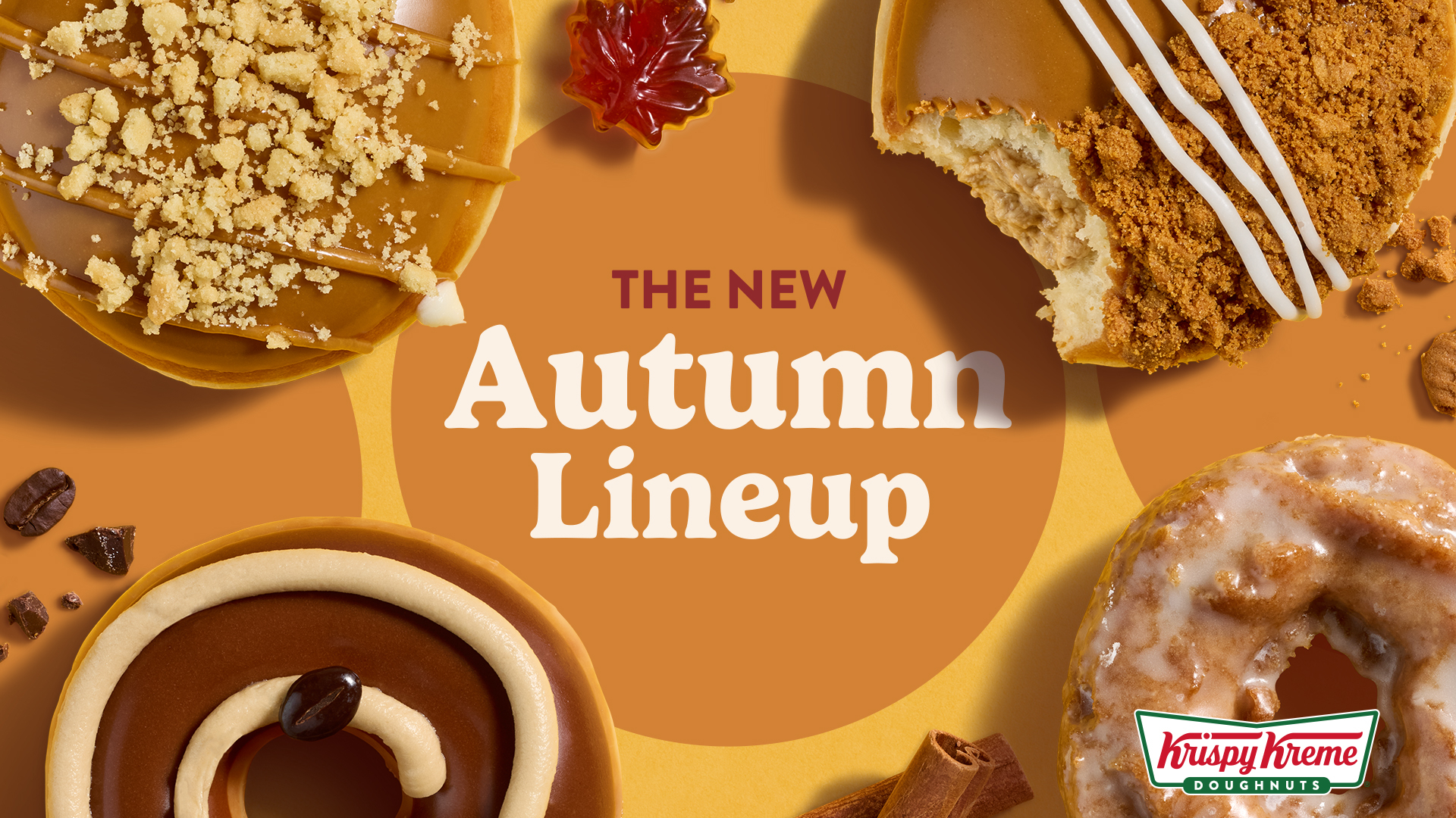 Four decorated donuts arranged on an orange background with the text The New Autumn Lineup and the Krispy Kreme logo in the bottom right corner to promote the Krispy Kreme Autumn collection