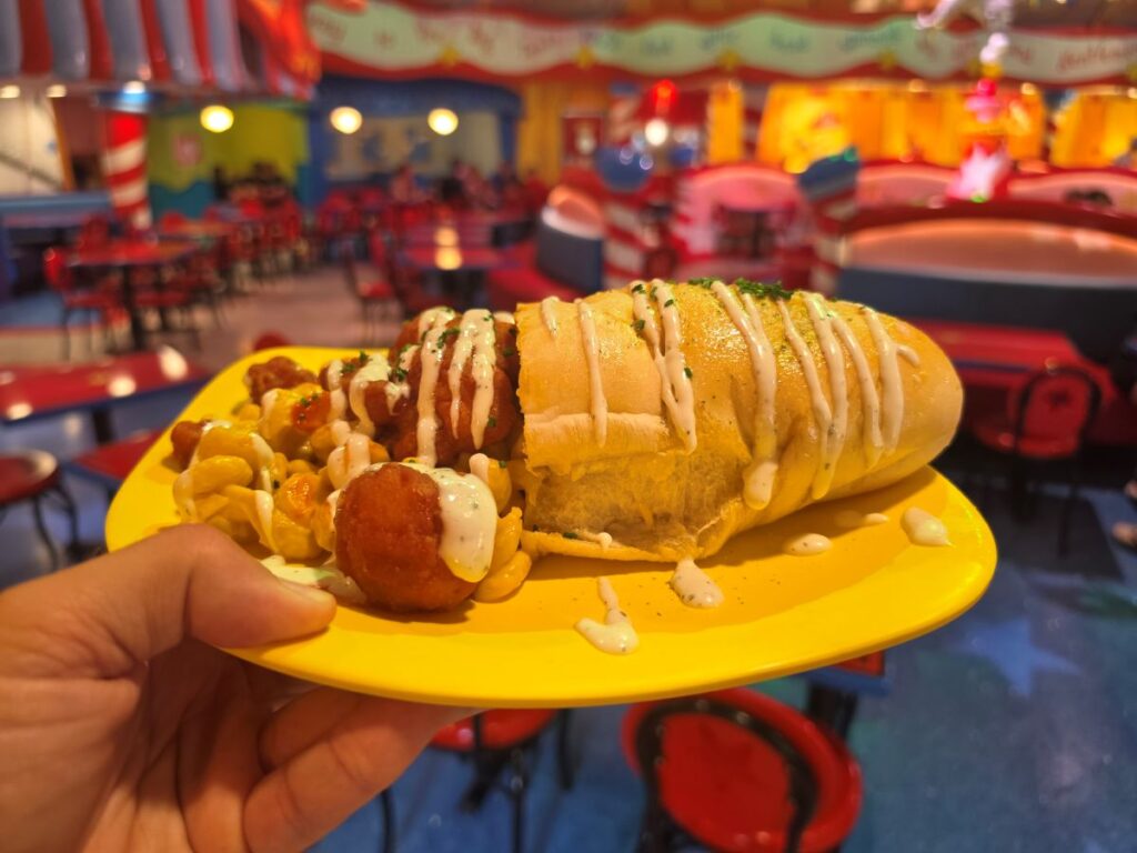 Morris's Mac-nificent Mac and Cheese Cone on a yellow plate with the vibrant Circus McGurkus Cafe Stoo-pendous dining room blurred in the background.