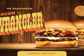 A Whataburger Bacon Wrangler burger with double patties, bacon, crispy onion strings, and cheese on a wooden table against a rustic wood background.