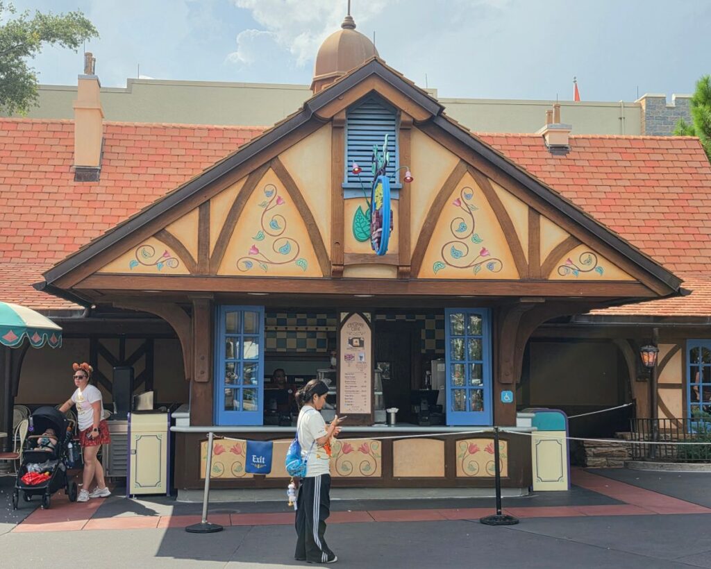 Exterior view of Cheshire Café quick-service kiosk with cottage architecture at Magic Kingdom in Walt Disney World.