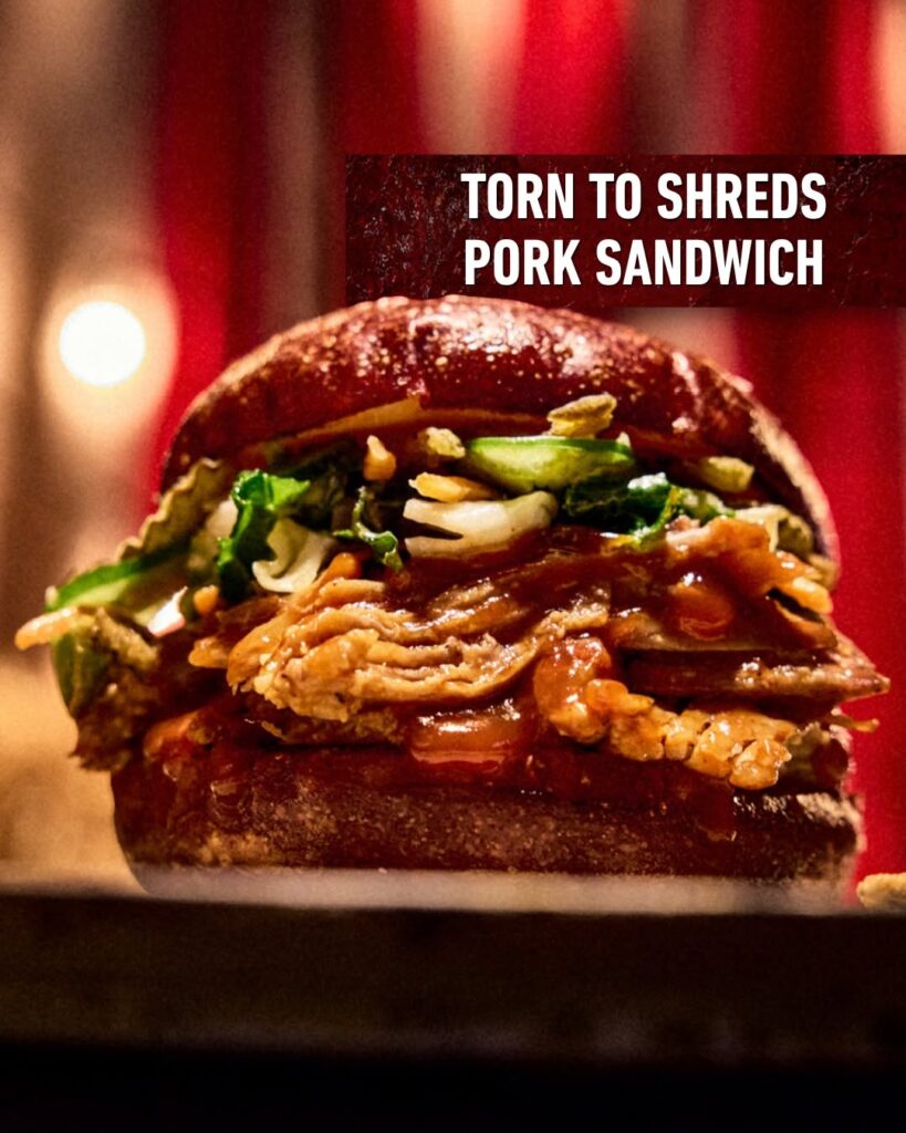 Close-up of the Torn to Shreds Pork Sandwich layered with pulled pork, sauce, and toppings on a toasted bun for Halloween Horror Nights 35.