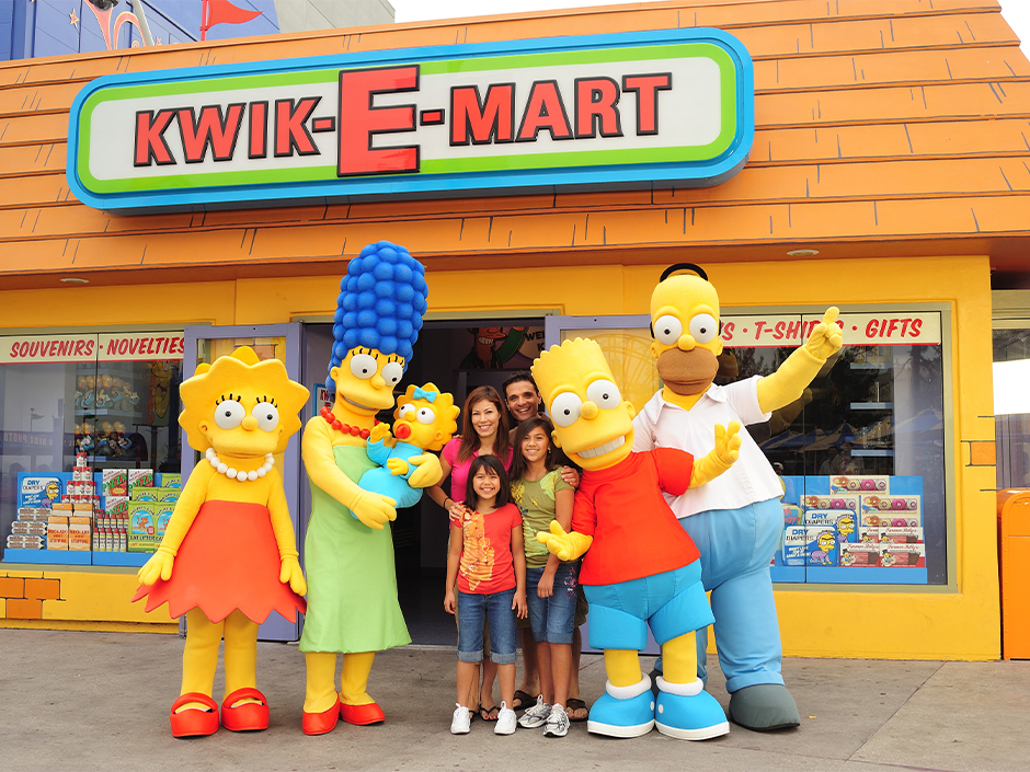 A family taking a photo with costumed characters of The Simpsons family outside the Kwik-E-Mart store.