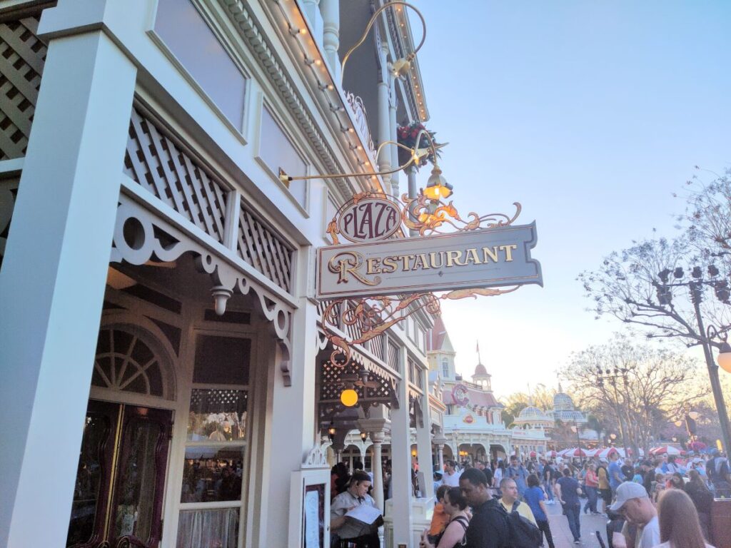 The exterior entrance sign for The Plaza Restaurant on Main Street, U.S.A. at Magic Kingdom during daytime.