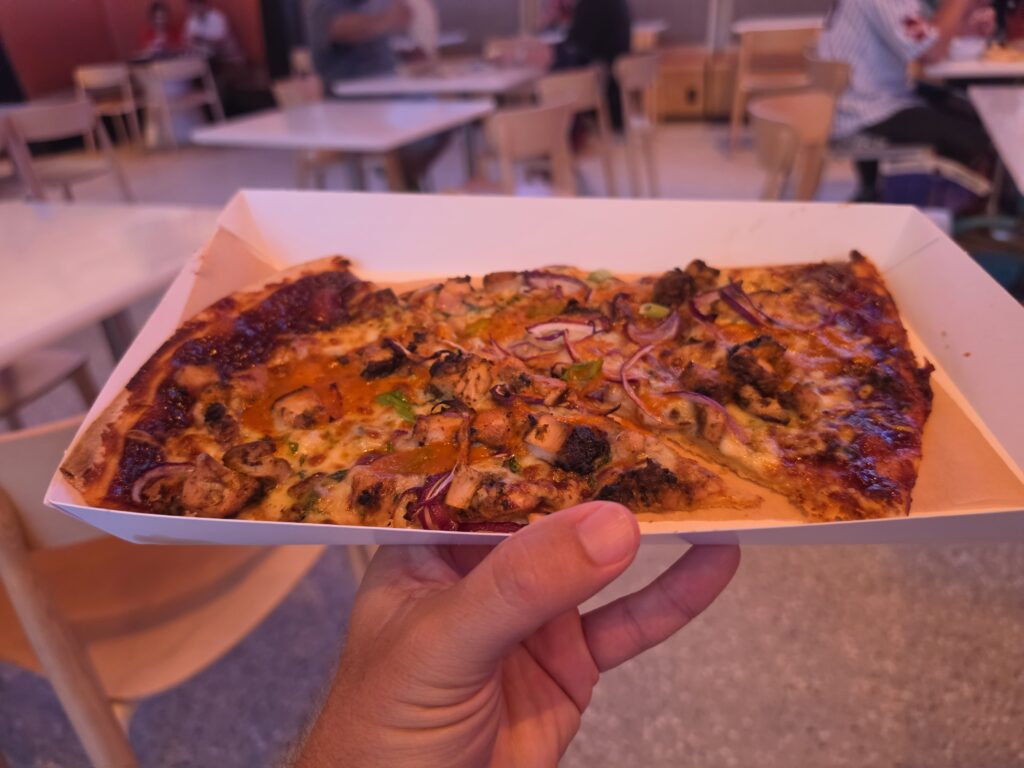 Front-facing shot of BBQ Braai Chicken Pizza featuring diced chicken, melted cheese, and red onions served at Epcot International Food & Wine Festival.