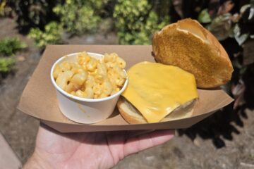A Beyond Burger with melted cheese and an open top bun next to a cup of mac and cheese in a paper tray at Aquatica Orlando