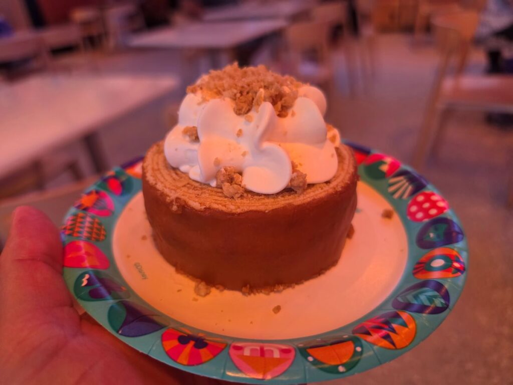 Close-up side view of the Caramel-Apple Cheesecake Baumkuchen dessert served on a colorful Disney Parks paper plate at Connections Eatery.