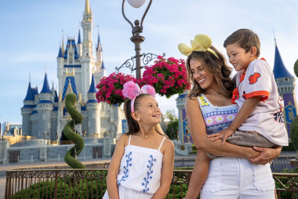 Disney World spring offers promotional image with an adult and two kids in front of Cinderella Castle
