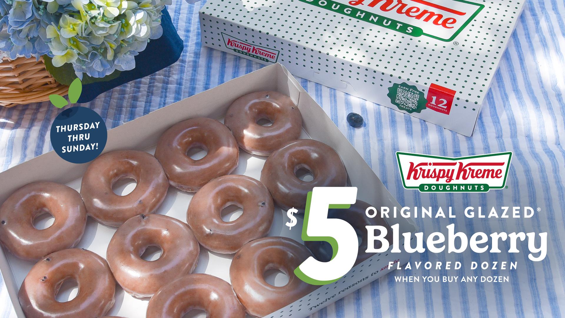 A box of Krispy Kreme doughnuts featuring a dozen original glazed blueberry doughnuts, with a floral arrangement and promotional text.