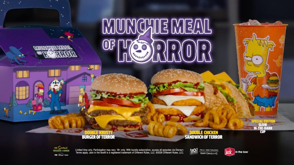 A Jack in the Box Munchie Meal of Horror featuring two burgers, tacos, curly fries, and a Simpsons-themed cup in a purple branded cardboard box.
