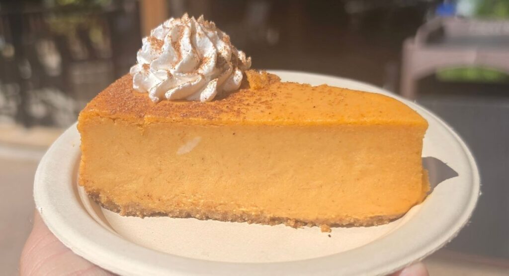 A piece of pumpkin cheesecake is shown on a white paper plate