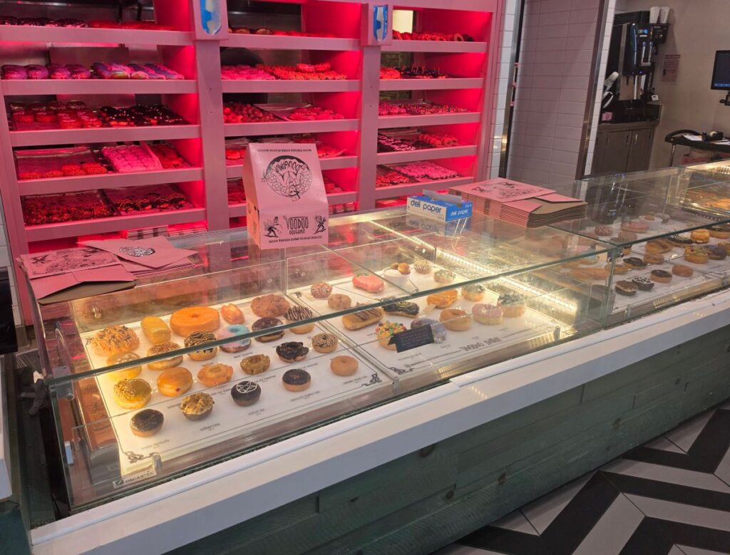 Glass display case filled with fresh pastries inside Voodoo Doughnut CityWalk Orlando