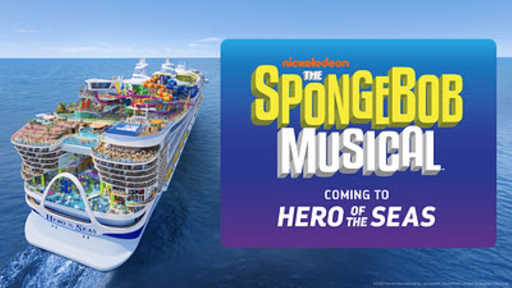 A large cruise ship sails on the ocean next to a blue sign announcing The SpongeBob Musical is coming to the Hero of the Seas cruise ship vessel.